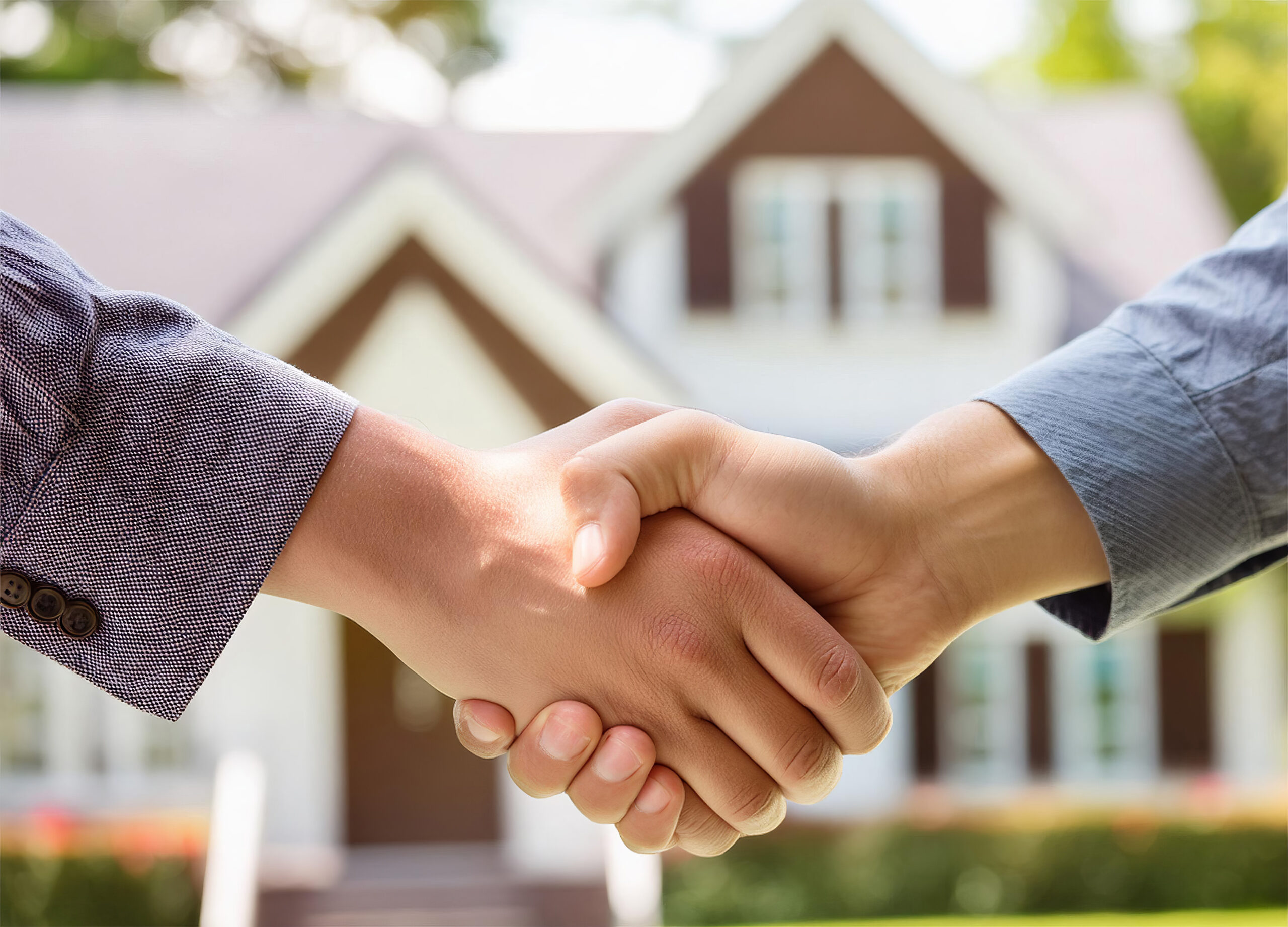 Close up of handshake with house for sale in background