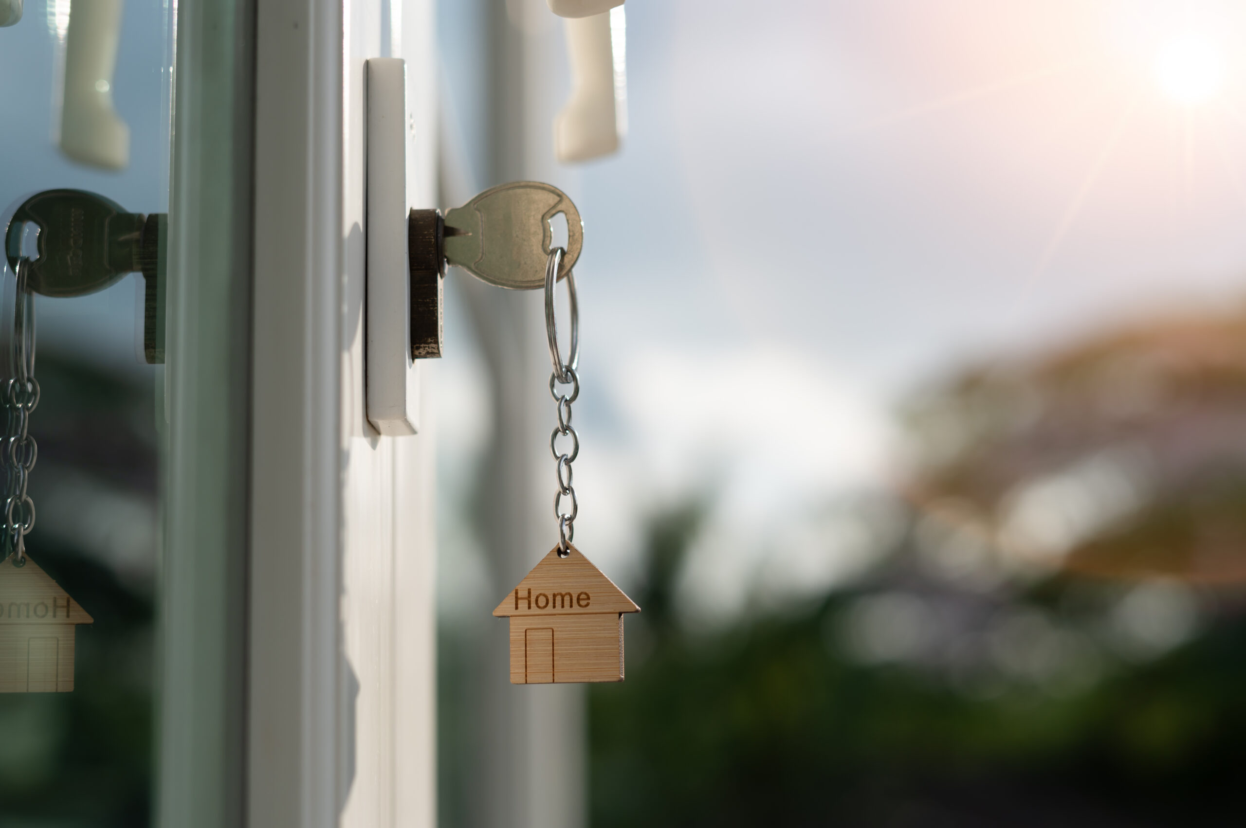 Landlord key for unlocking house is plugged into the door. Second hand house for rent and sale. keychain is blowing in the wind. mortgage for new home, buy, sell, renovate, investment, owner, estate